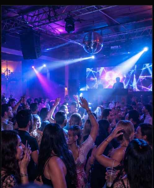 Público disfrutando de una fiesta con iluminación azul y violeta